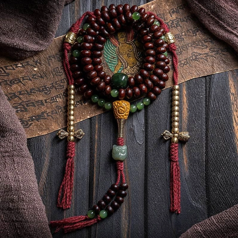 Tibetan 108 mala bracelet with purple bodhi seeds, hetian jade beads, and copper dorje charm in flat lay arrangement