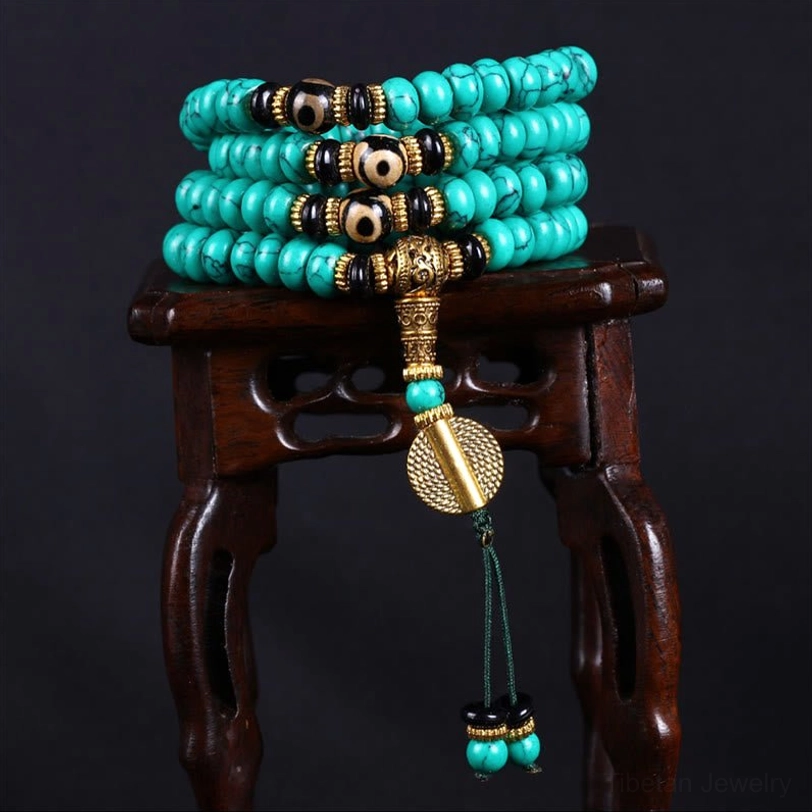 Full 108-bead turquoise mala necklace hanging with tassel charms and metal guru bead