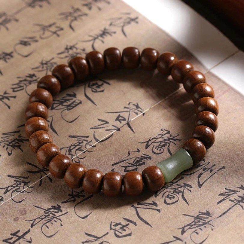 Single Tibetan Abelia Biflora wood bracelet with light green jade bamboo-joint spacer on cultural paper background