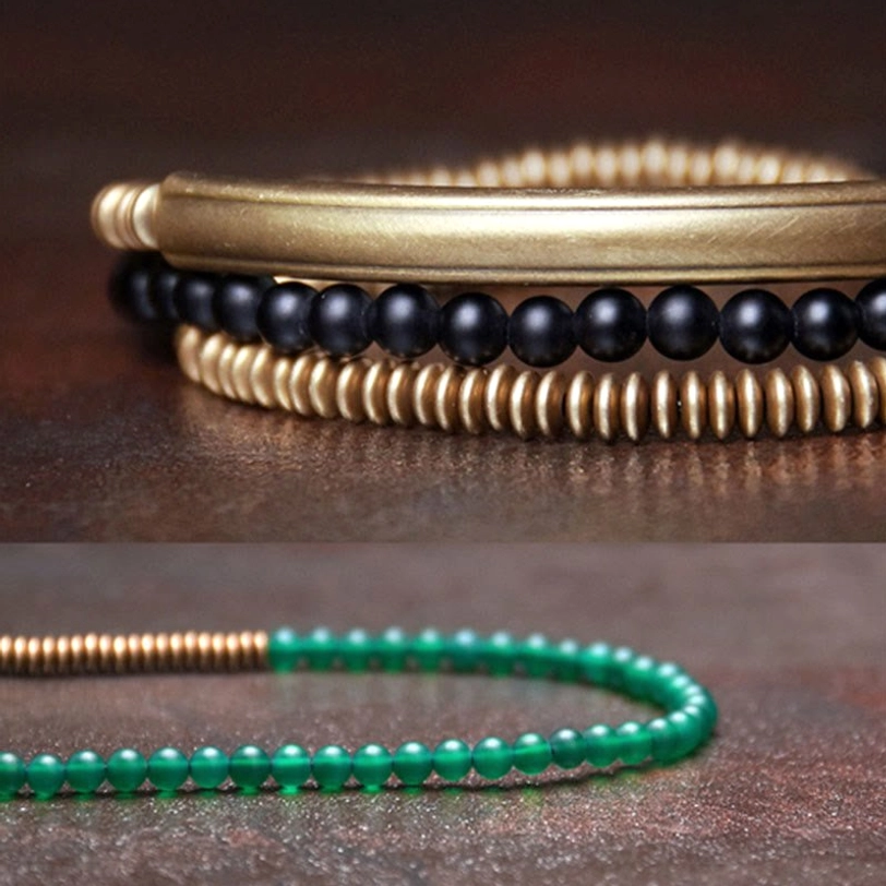 Close-up detail of Tibetan bracelet components showing polished brass tube, black agate beads, and brass spacers with smooth metal texture
