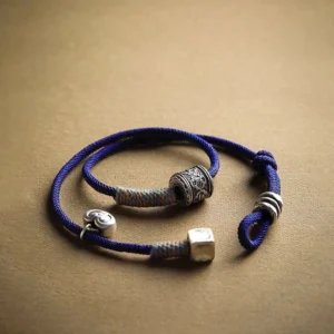 Close-up view of silver barrel beads and flat square charm on royal blue Tibetan amulet bracelet with adjustable slide lock closure