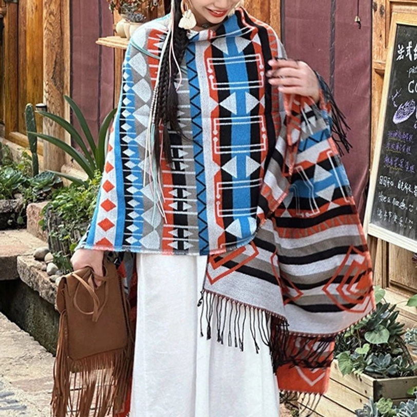 Arrow tribal geometric poncho close-up front view, blue-brown ethnic prints, paired with fringe handbag, coffee shop setting