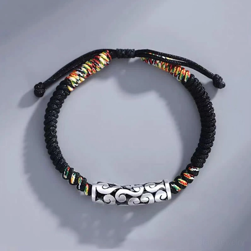 Full overhead view of handmade tibetan luck bracelet with adjustable pull knots and complete braided design on gray surface