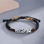 Tibetan copper auspicious cloud luck string bracelet with silver embossed cloud charm and colorful woven accents on minimalist gray surface