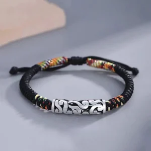 Tibetan copper auspicious cloud luck string bracelet with silver embossed cloud charm and colorful woven accents on minimalist gray surface