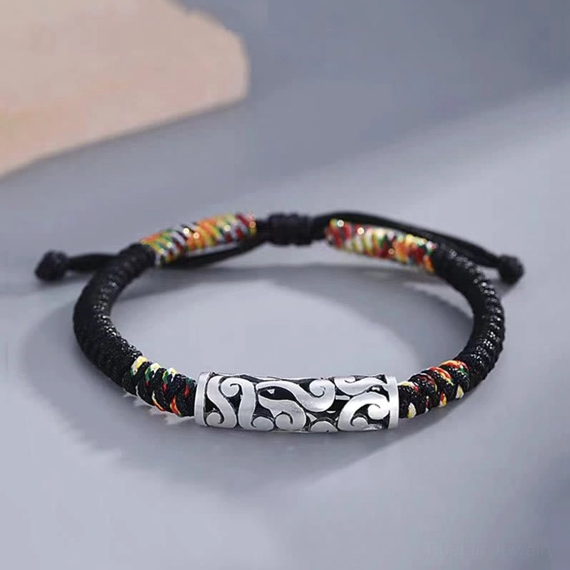 Tibetan copper auspicious cloud luck string bracelet with silver embossed cloud charm and colorful woven accents on minimalist gray surface
