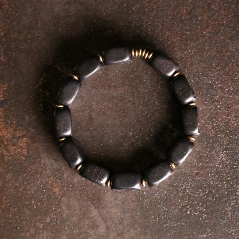 Top-down overhead flat lay view of complete ebony wood balance bracelet with round bronze gold bead spacers