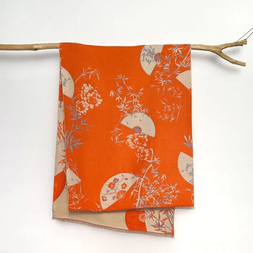 Coral Tibetan bamboo peony reversible scarf on wooden hanger showing tangerine orange base with cream and grey prints