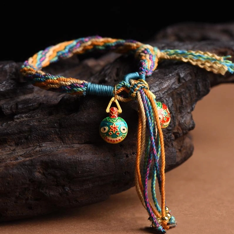 Tibetan family blessing bracelet with multicolor twisted rope and large protective beast enamel pendant on wooden surface