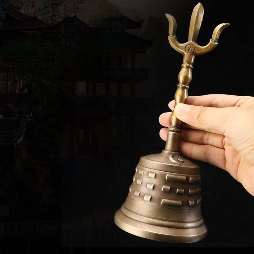 Handmade Tibetan copper meditation bell with vajra dorje handle, antique bronze finish with bagua patterns, held in traditional low angle view