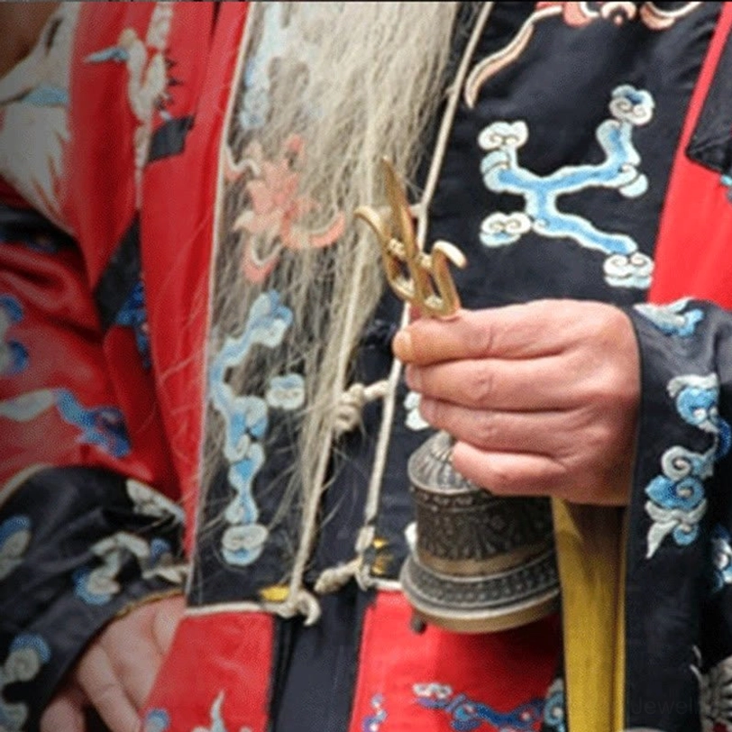 Tibetan Buddhist ritual bell and dorje set held by practitioner in traditional embroidered ritual clothing, authentic use demonstration
