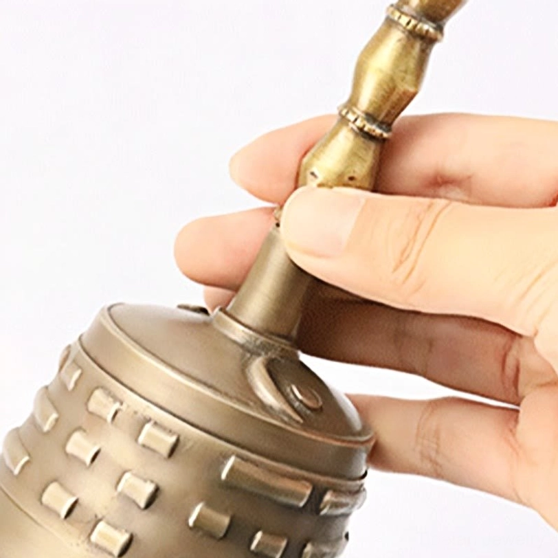 Close-up detail of Tibetan meditation bell with bamboo-style handle and embossed bagua decoration, copper ritual instrument