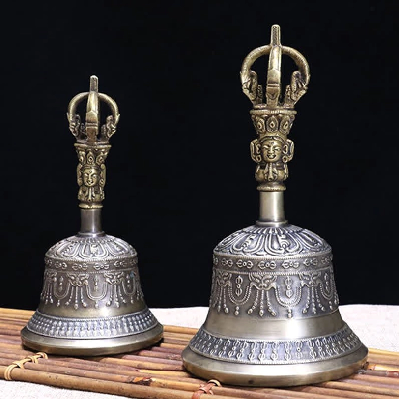 Two Tibetan ritual meditation bells with matching embossed decorative patterns displayed in parallel front view