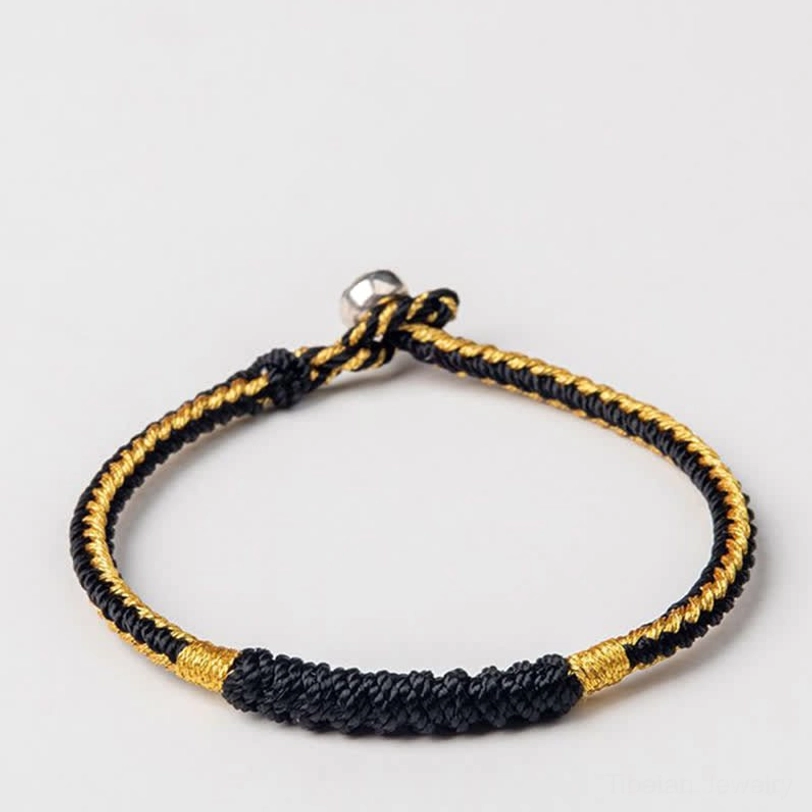 Tibetan black string protection bracelet with braided rope design and silver adjustable clasp on white background