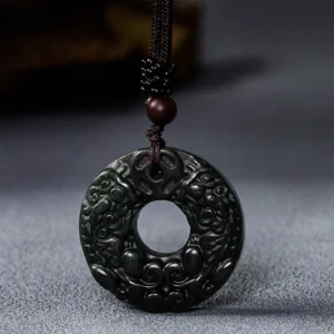 Close-up of Pixiu carved relief on black-green jade peace buckle showing detailed traditional engravings