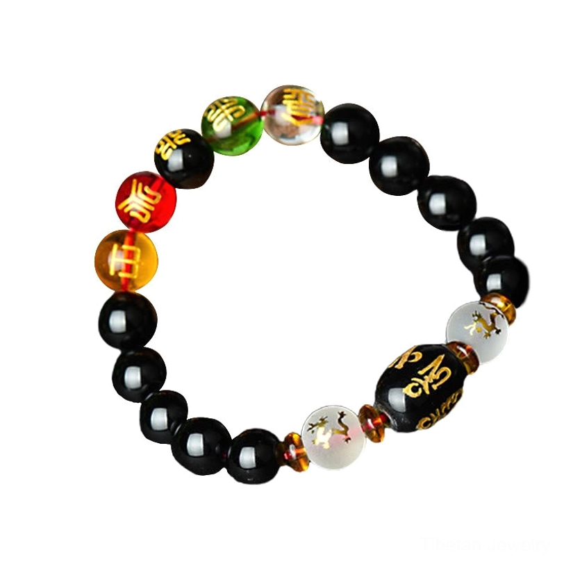 Tibetan black onyx bracelet with 10mm beads and hand-engraved mantra barrel displayed on pure black background, front flat-lay view