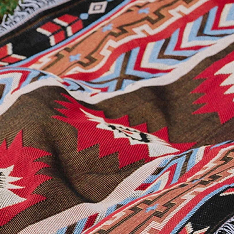 Close-up texture of Tibetan blanket fabric showing 3D jacquard weave with red brown black geometric motifs and woven detail