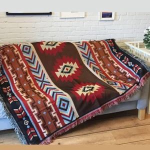 Authentic Tibetan woven blanket featuring symmetric tribal motifs and traditional fringe hem on wooden floor