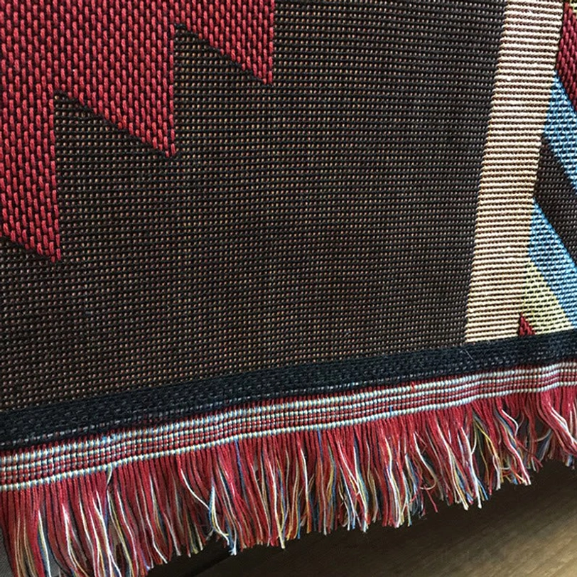 Tibetan geometric blanket close-up showing dark brown base with red geometric accents and fringe