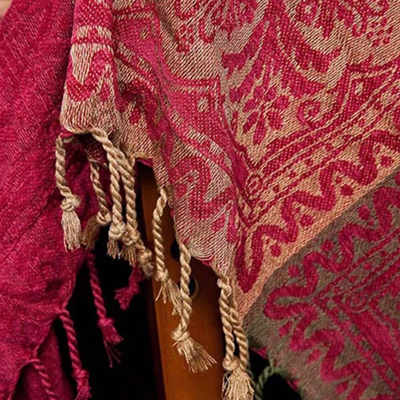 Twisted cotton tassel detail of Tibetan throw blanket showing intricate hand-tied fringe and red damask pattern