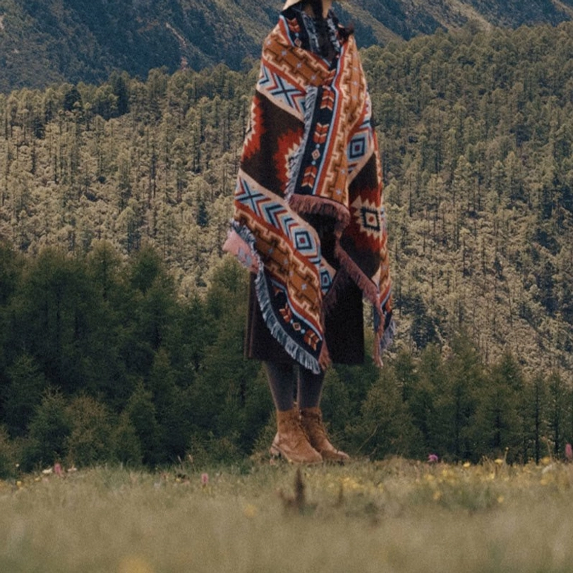 Tibetan ethnic blanket worn as shoulder wrap shawl showing traditional fringed border and tribal pattern
