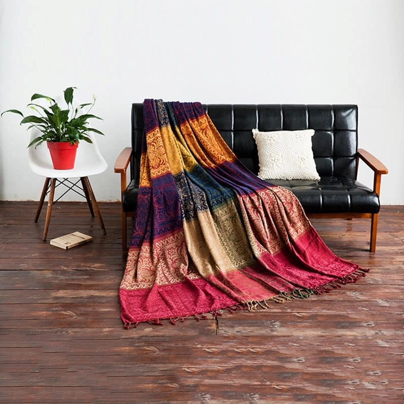 Tibetan handwoven throw blanket draped over black leather sofa with matching block damask pattern and tasseled edges