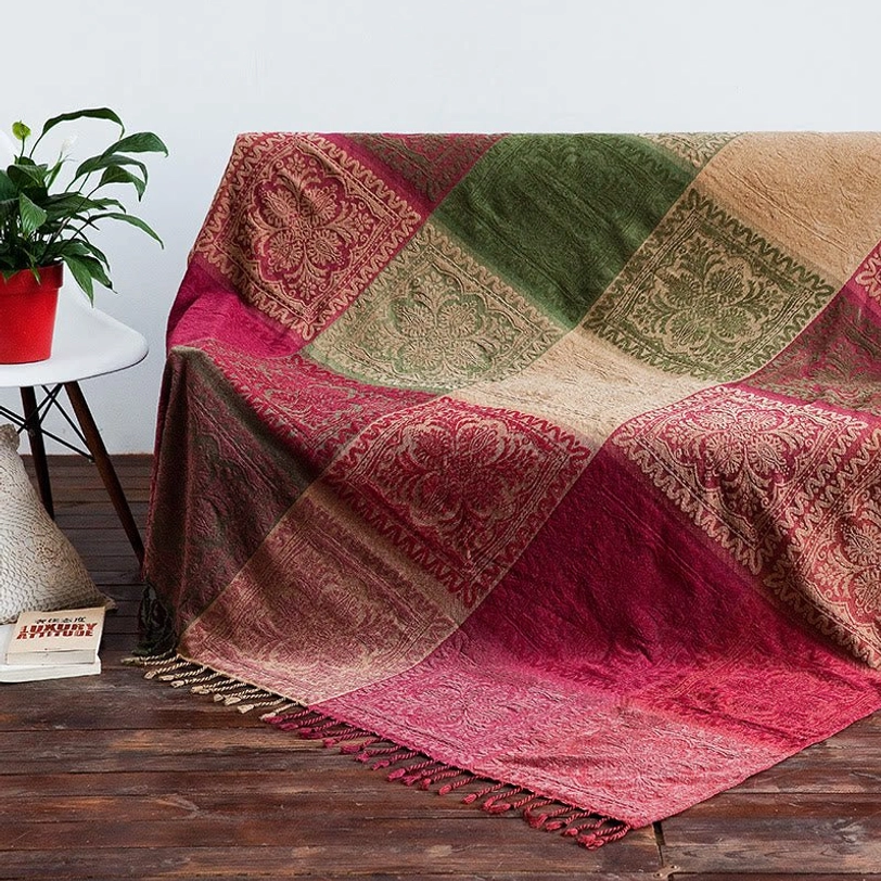 Tibetan handwoven throw blanket draped over sofa arm, showing patchwork ethnic color layout and braided tassel trim detail