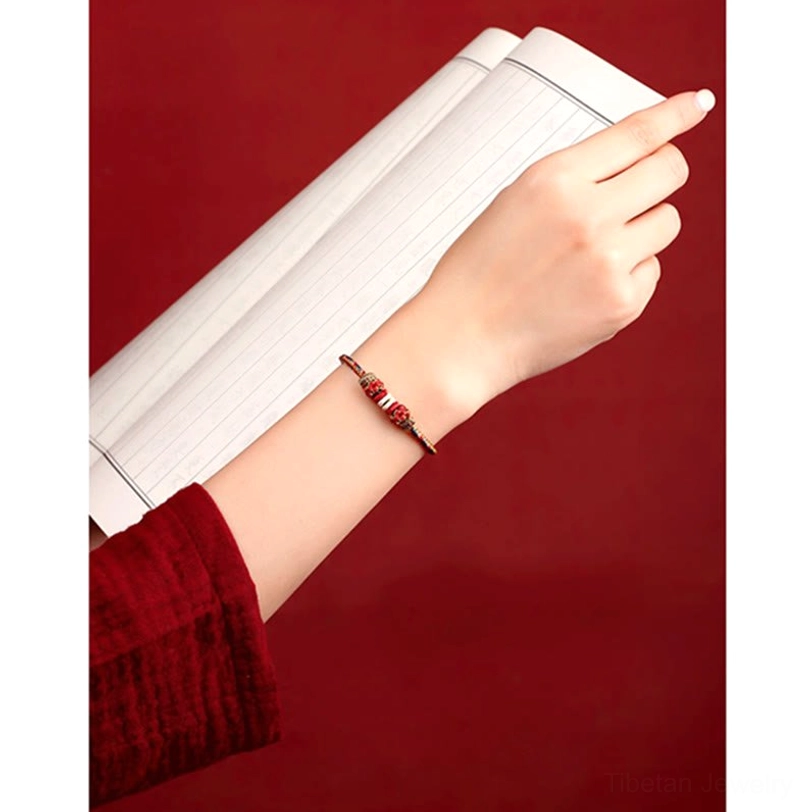 Slim multicolor woven Tibetan protection bracelet on wrist with red background