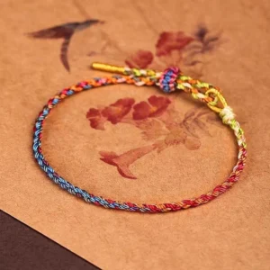 Tibetan lucky rope bracelet featuring gold-yellow rope ends and traditional woven decorative knot on vintage background