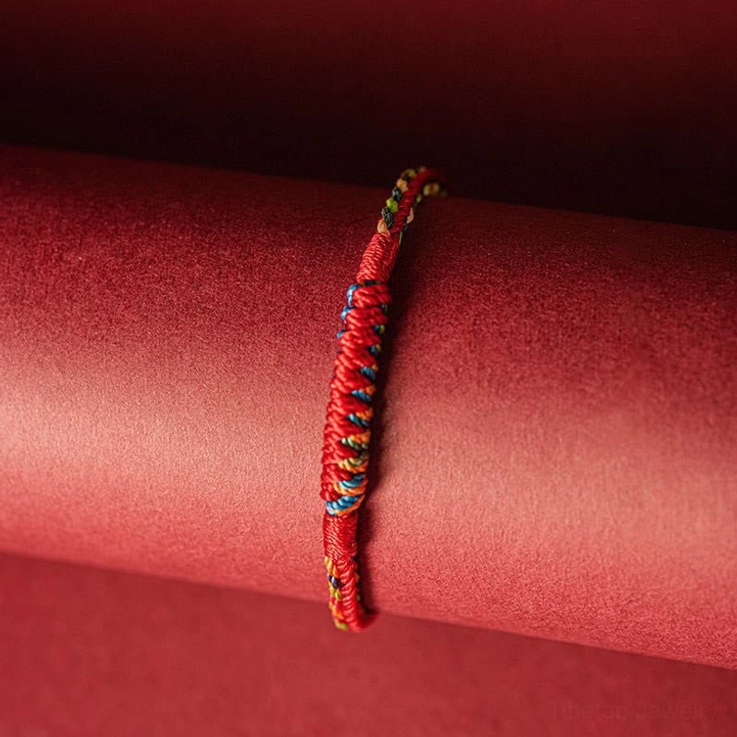 Handmade five-color woven protection bracelet hanging on display prop showing complete circular design