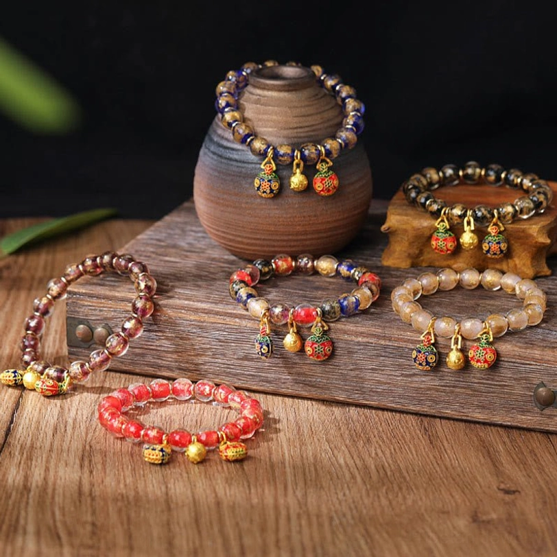 Assorted swallowing beast charm beaded bracelets in multiple colors with pottery vase display