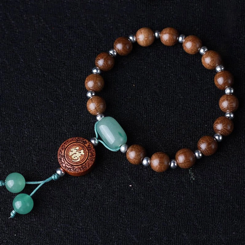 Looped abelia biflora wood bracelet on black background displaying natural six-line texture, silver spacers, and green blessing beads