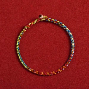 Flat lay of colorful woven Tibetan bracelet showing gradient thread details and metal toggle clasp