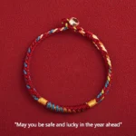 Tibetan multicolored blessing bracelet with King Kong knot and metal clasp, overhead flat lay view on red background