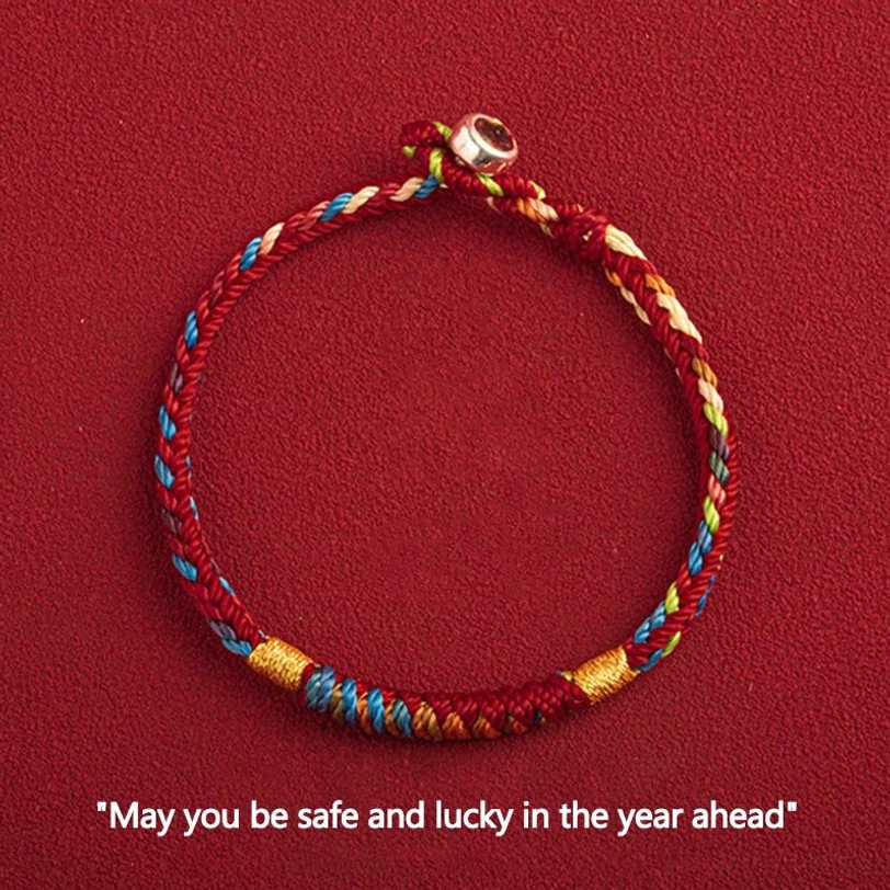 Tibetan multicolored blessing bracelet with King Kong knot and metal clasp, overhead flat lay view on red background