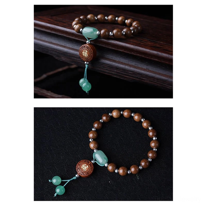 Partial view of tibetan blessing bracelet showing brown dragon wood beads, green jade accents, and fu charm pendant on dark surface