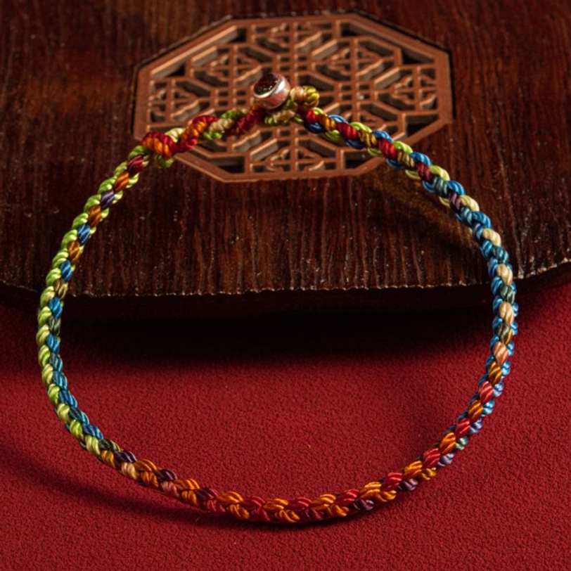 Tibetan hand-woven multicolor bracelet with silver clasp on red decorative background