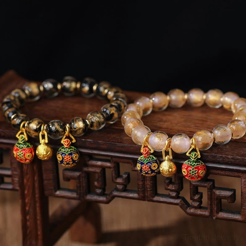 Two styles of swallowing beast beaded bracelets displayed on traditional wooden stand