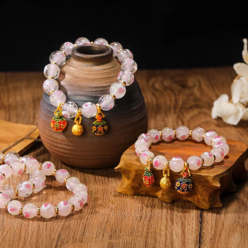 Multiple Tibetan blessing bracelets with fluorescent pink beads and ornate enamel pendants displayed overhead