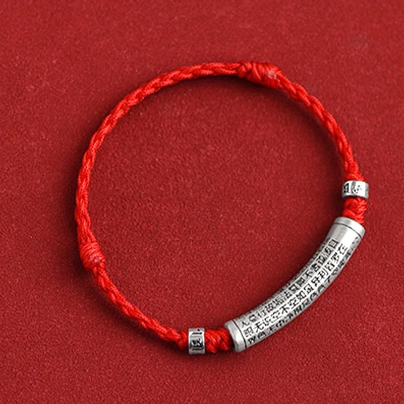 Tibetan blessing bracelet with braided red string and silver charm displaying spiritual protection symbolism