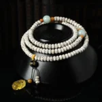 Tibetan bodhi seed mala bracelet with amber accent and pixiu pendant, displayed on black ceramic meditation base