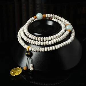 Tibetan bodhi seed mala bracelet with amber accent and pixiu pendant, displayed on black ceramic meditation base