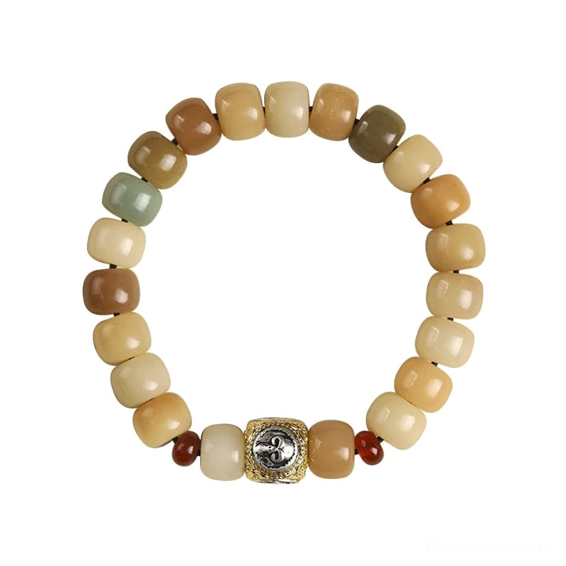Tibetan bodhi seed bracelet with carved metal focal charm and red accent beads, flat lay tabletop view