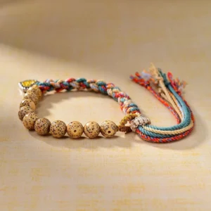 Side view of handwoven Tibetan protection bracelet showing detailed bodhi seed beads, colored rope weave, and metal goddess amulet