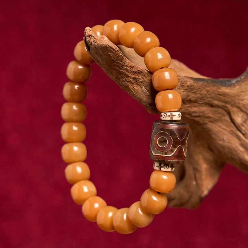 Tibetan spiritual bracelet worn on hand - Bodhi seed and Dzi bead displayed on wooden hand prop with red velvet background