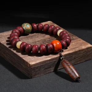 Tibetan bodhi seed dzi bead dancing lion bracelet with reddish-brown beads and agate ornaments displayed on wooden block