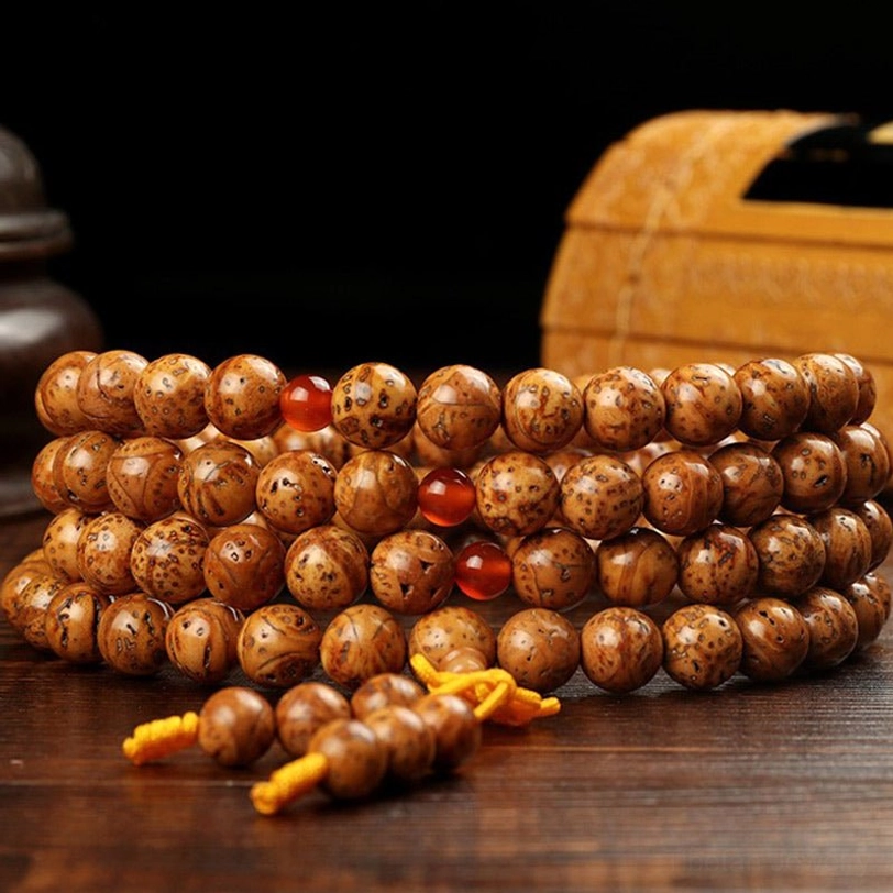 Authentic bodhi seed prayer mala beads arranged on wooden table with storage box, demonstrating natural porous texture and traditional tassel