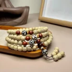 108 Bodhi seed mala bracelet with hand-painted Dzi bead, displayed on wooden surface showing intricate beadwork and tassel pendant
