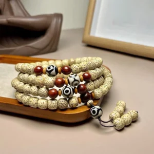 108 Bodhi seed mala bracelet with hand-painted Dzi bead, displayed on wooden surface showing intricate beadwork and tassel pendant