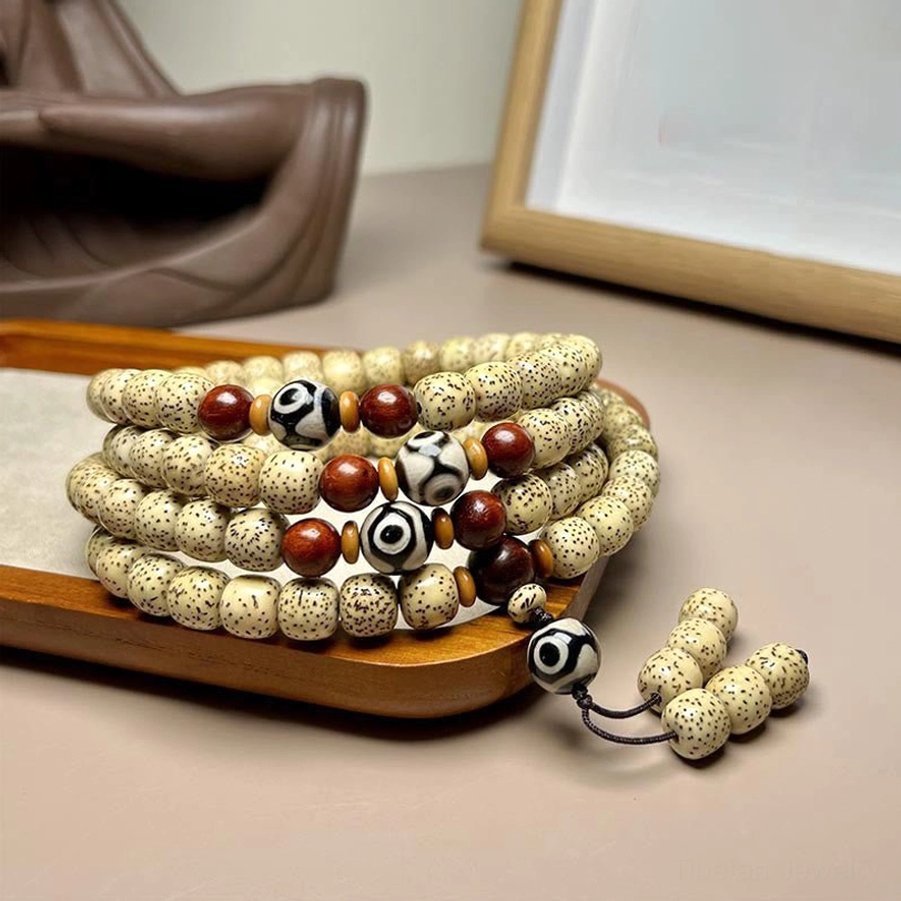 108 Bodhi seed mala bracelet with hand-painted Dzi bead, displayed on wooden surface showing intricate beadwork and tassel pendant